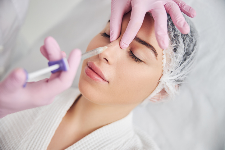 Une femme reçoit une injection de produit de comblement du nez non chirurgicale d'une esthéticienne agréée