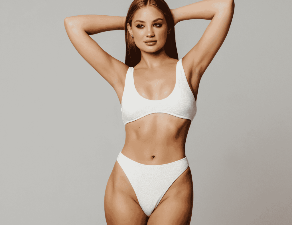 Femme en bikini blanc avec une partie médiane tonique, illustrant les résultats du remodelage corporel d'AirSculpt Toronto.